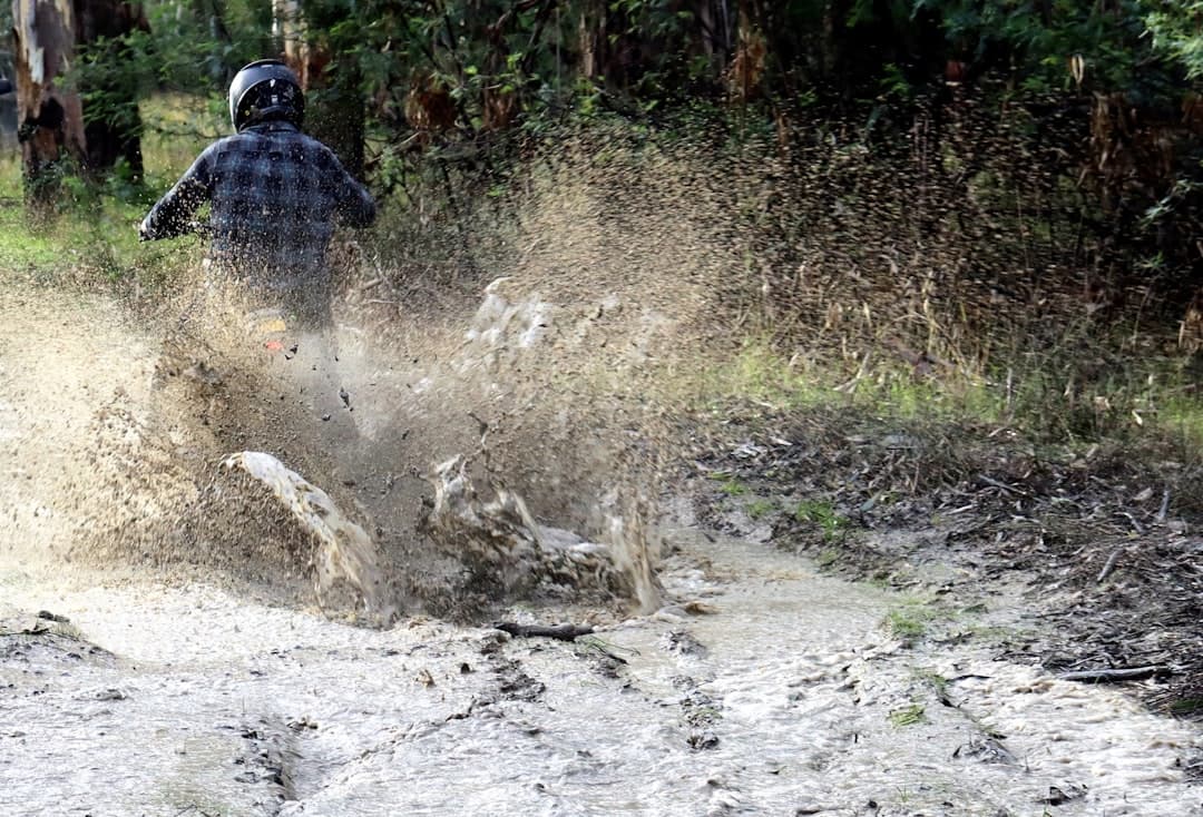 a man riding a dirt bike through a puddle of mud