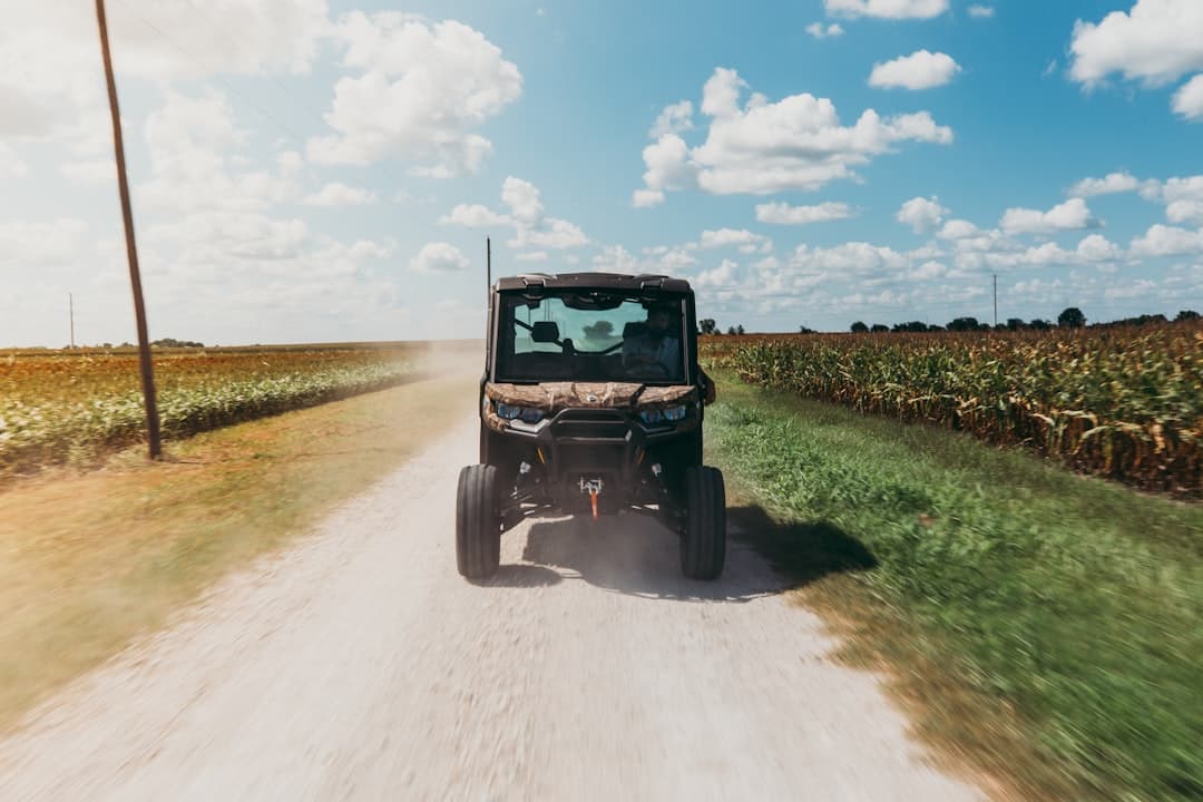 black and gray golf cart on green grass field under blue and white sunny cloudy sky