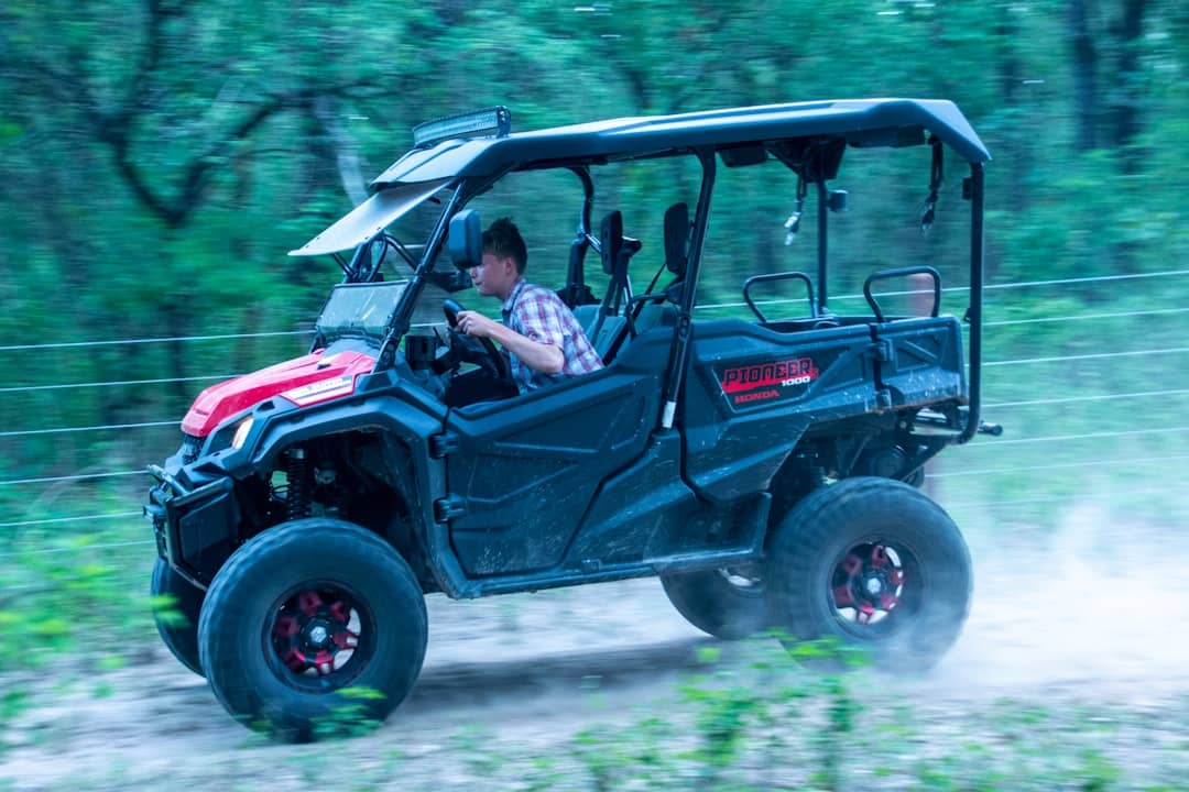 a man driving a red and black four - wheeler on a dirt road