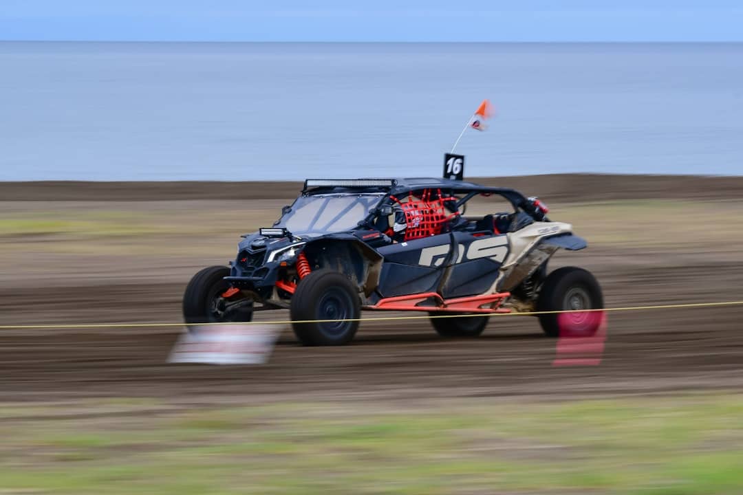 A side-by-side off-road vehicle racing on a dirt track