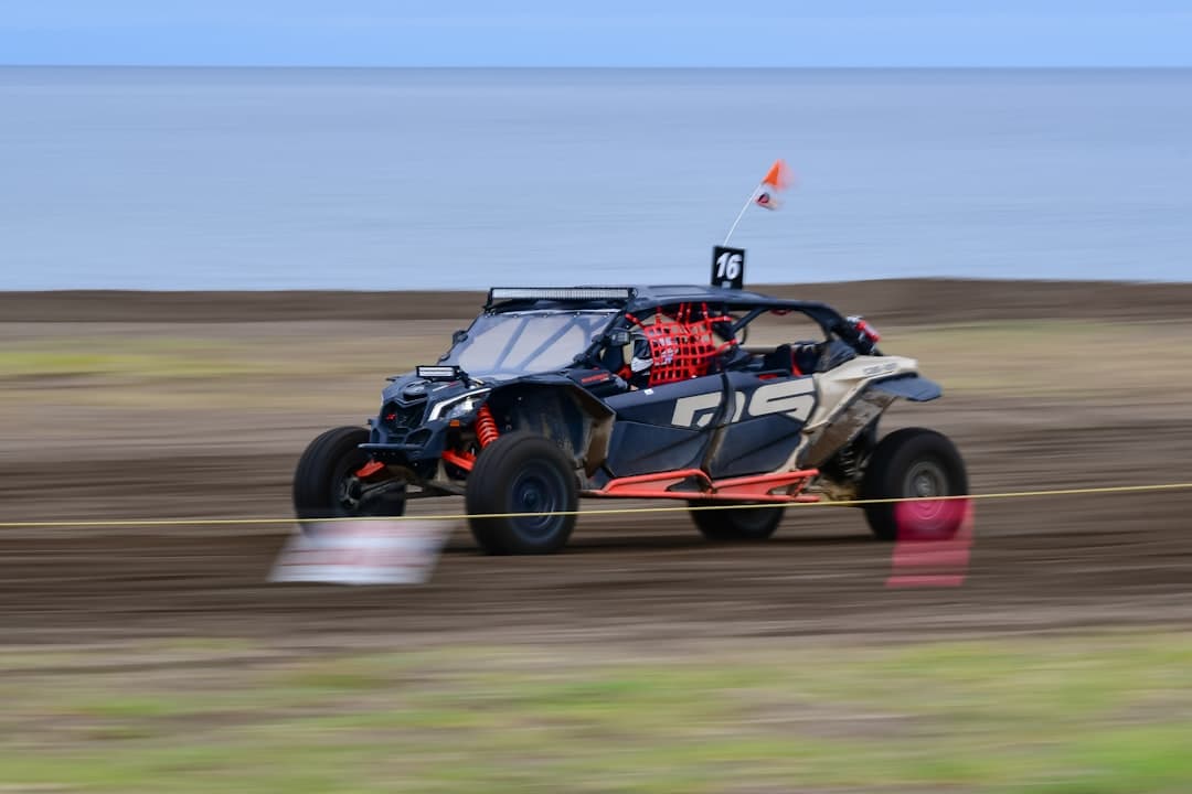 A side-by-side off-road vehicle racing on a dirt track